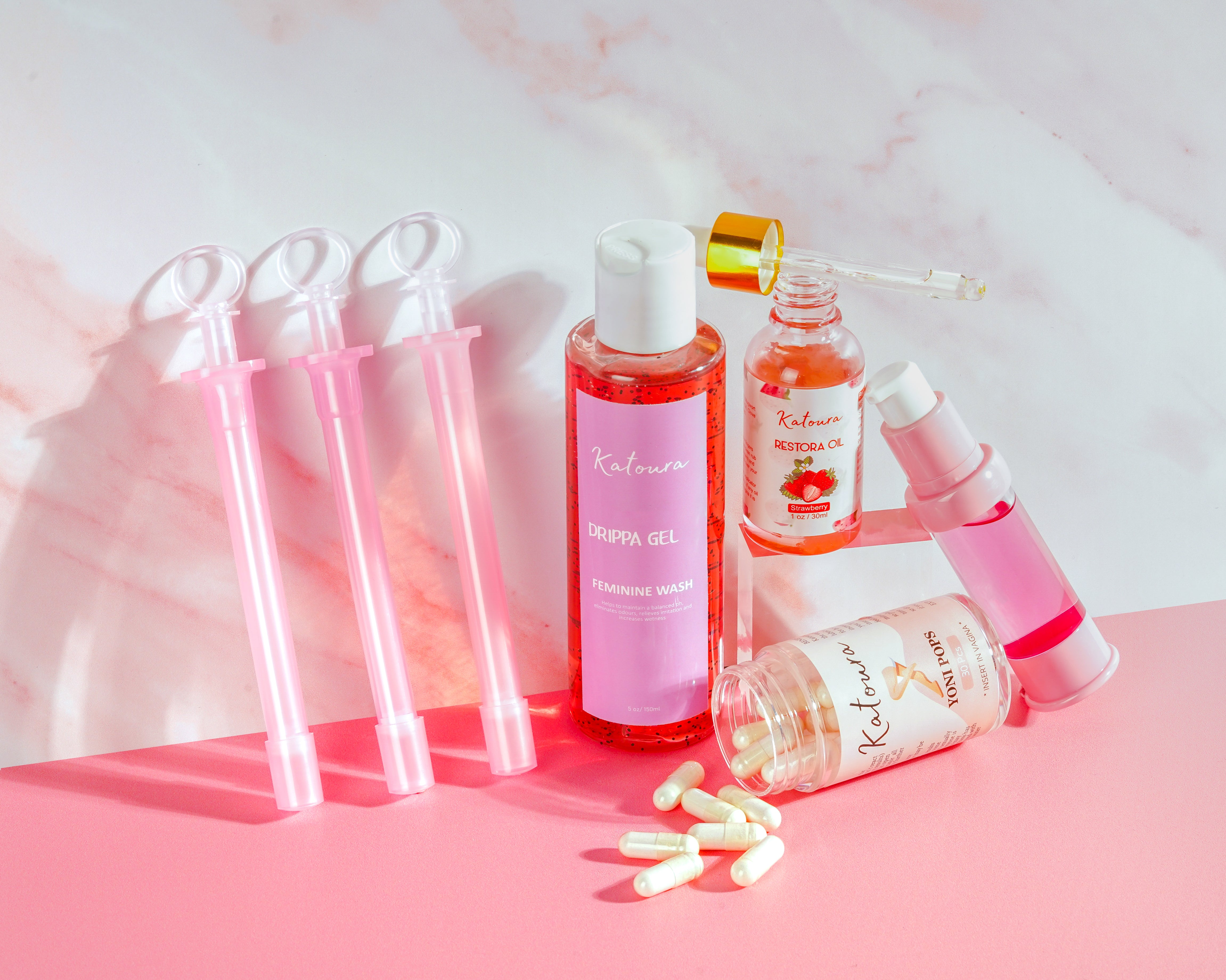 Assorted skincare and wellness products displayed on a pink surface with a marble background.